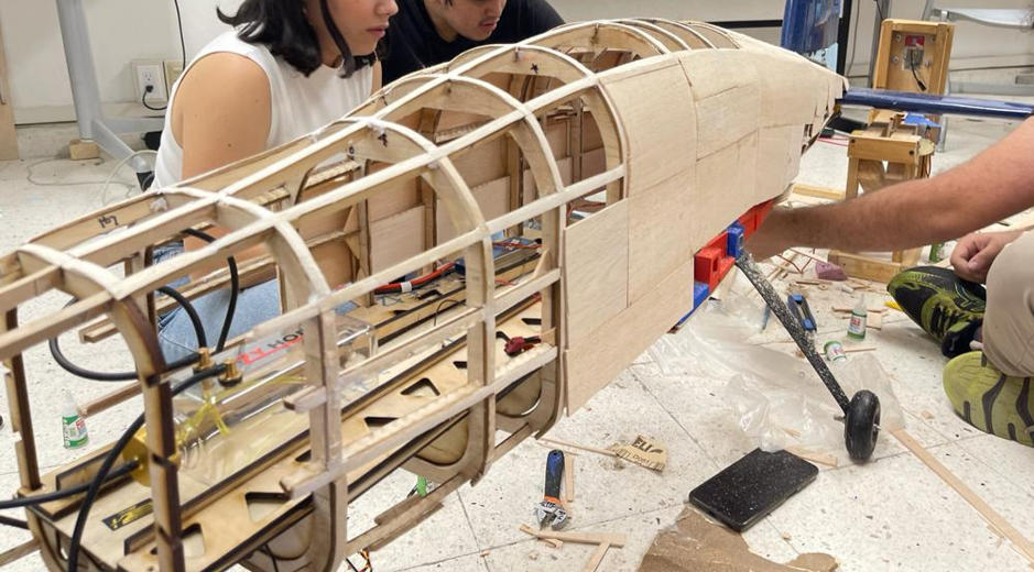 Wooden aircraft fuselage structure with team members assembling components
